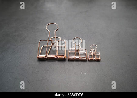 Rose Gold Metall Clips von 3 auf den grauen Schreibtisch Stockfoto