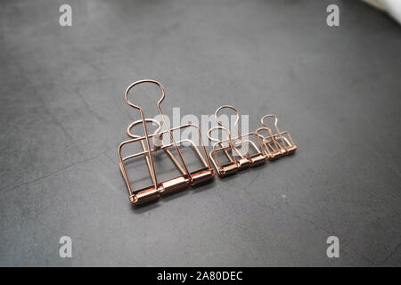 Rose Gold Metall Clips von 3 auf den grauen Schreibtisch Stockfoto