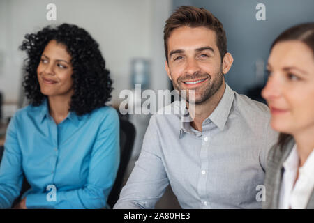 Lächeln, Geschäftsmann, Sitzen mit Kollegen im Büro Stockfoto