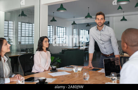 Manager im Gespräch mit seinen Mitarbeitern um ein Büro Tabelle Stockfoto