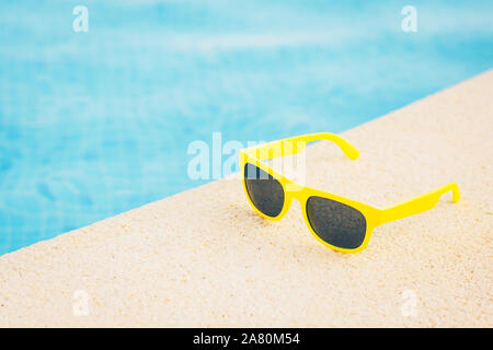 Gelbe Sonnenbrille in der Nähe der blauen Pool Stockfoto