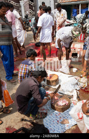 Devotees schneiden Ziegenfleisch während Kutti Kudithal Festival in Trichy, Tamil Nadu, Indien Stockfoto