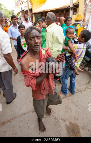 Armer Mann mit den abgetrennten Kopf einer Ziege zu Fuß auf der Straße während Kutti Kudithal Festival in Trichy, Tamil Nadu, Indien Stockfoto