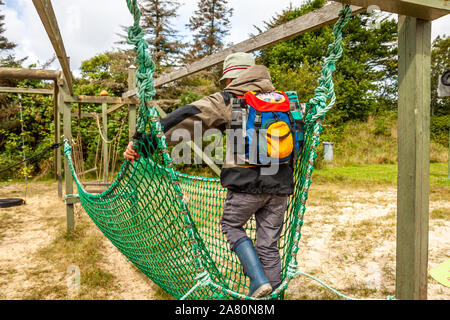 Kleiner Junge klettern auf das Netz im Adventure Park. Stockfoto