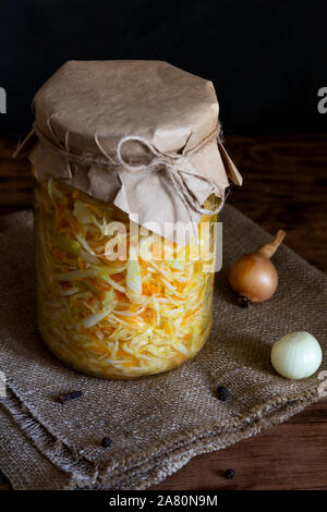 Fermentiertes Gemüse. Mit Karotten in einem Glas auf einem dunklen Hintergrund Sauerkraut. Vertikale Ausrichtung Stockfoto