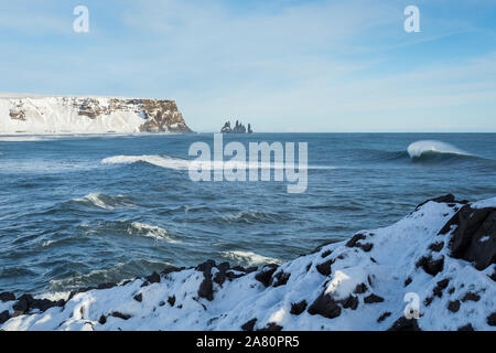 Wellen in Reynisfjara vom Kap Dyrholaey im Süden Islands. Reynisdrangar sea Stacks. Sonnig und verschneiten Tag. Stockfoto