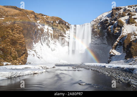 Regenbogen in der Gischt Wasserfall Skogafoss, in Island. Sonnigen Tag Winter, verschneite Landschaft. Stockfoto