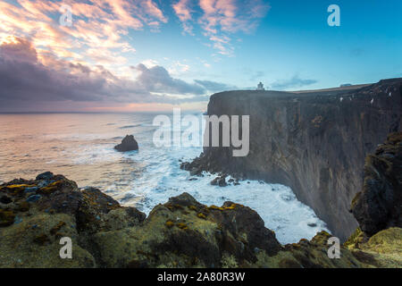 Kap Dyrholaey Leuchtturm im Süden Islands. Bewölkt, Sonnenuntergang von der Klippe. Starke Wellen. Stockfoto