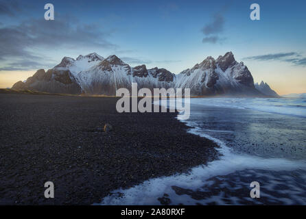 Vestrahorn Snowy Mountain, in Stokknes, Südosten Islands. Nach dem Sonnenuntergang. Sanddünen, Gras und das Meer. Stockfoto