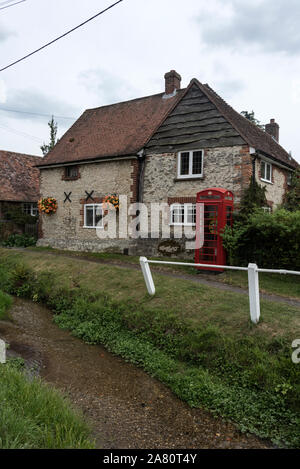 Ein Feuerstein, aus Stein gebauten Ferienhaus mit seinen floralen Blumenampeln neben einem Strom in einem kleinen Weiler Cuxham auf die wichtigsten Watlington - Stadhampton Straße in ea Stockfoto