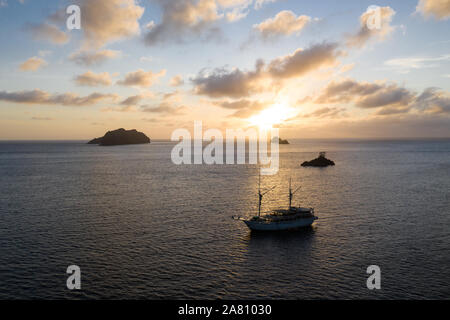 Eine friedliche Sonnenuntergang Silhouetten Kalkstein Inseln und einen pinisi Schoner in Raja Ampat, Indonesien. Dieser Bereich birgt außergewöhnliche Artenvielfalt des Meeres. Stockfoto