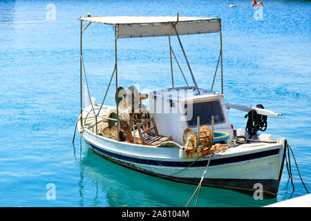 Ein kleines, altes, hölzernes Fischerboot mit betallic Rollen für bis reeling Fischernetze, die schwankt in Bewegung auf den Wellen an der Pier. Stockfoto