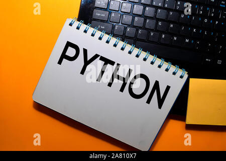 Python auf Buch mit Laptop Tastatur Hintergrund schreiben Stockfoto