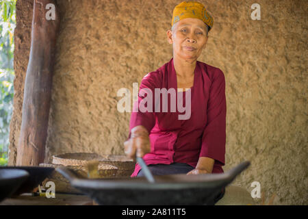 Bali, Indonesien - 13. September 2019: Alte Frau rösten luwak Kaffee Bohnen in Ubud. Luwak Kaffee ist sehr teuer und berühmten Balinesischen cofee Stockfoto