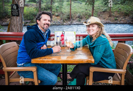 Ein Mann und eine Frau an einem Tisch auf der Terrasse entlang der Chewuch Fluss in Winthrop, Washington am Alten Schulhaus Brauerei, USA sitzen. Stockfoto