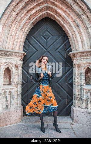 Schöne skinny albanische Mädchen posiert und zeigt die Orange Blue ornament Kleid Stockfoto