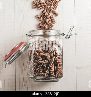 Auf einer weißen Tafel rustikalen Tisch ein Glas Glas mit italienischer Pasta Stockfoto