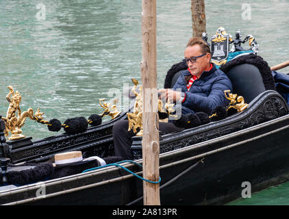 Eine venezianische Gondoliere eine Auszeit nimmt, um das Papier zu lesen, während die Preise in seinem Plüsch Gondel in der Nähe der Rialtobrücke in Venedig Italien warten Stockfoto