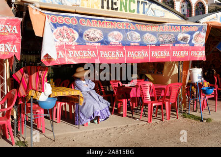 Lokale Frau sitzt auf der Terrasse in einem typischen Lokal am Strand von Copacabana, Bolivien Stockfoto