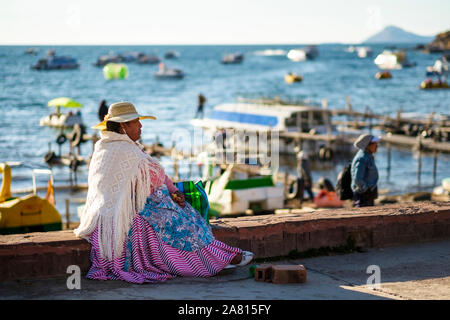 Lokale Frau tragen schicke Kleidung und Sitzen am Strand von Copacabana, Bolivien Stockfoto