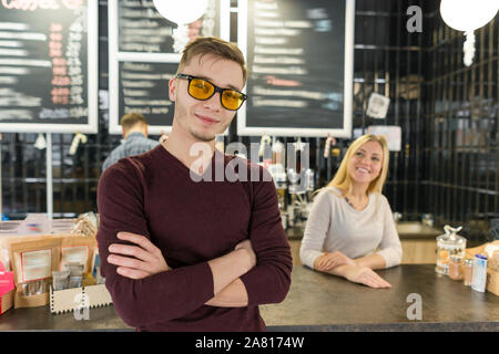 Junges Team von drei cafe Arbeitnehmern, Menschen aufwirft und lächelnd an Coffee Bar in der Nähe der Theke Stockfoto