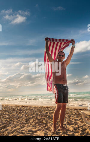 Varadero, Kuba, Jan 2013 - junge Mann wirft sein Badetuch am Strand nach aus dem Meer Stockfoto