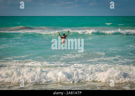 Männliche Urlauber im Meer winkte mit beiden Armen bis - Varadero, Kuba, Jan 2013 Stockfoto