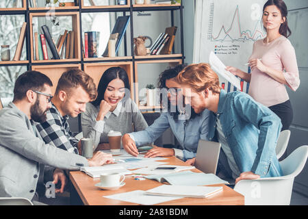 Startupers zusammen arbeiten im Büro sitzen Hobeln Projekt während schwangere Frau, Stockfoto