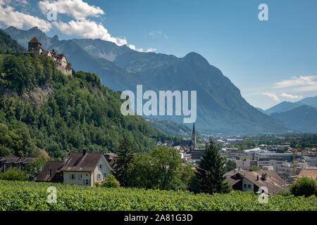 Eine Sommerlandschaft aus dem Fürstentum Liechtenstein. Schloss Vaduz auf einem grünen Hügel im Hintergrund das beeindruckende Bergmassiv der Alpen. Stockfoto