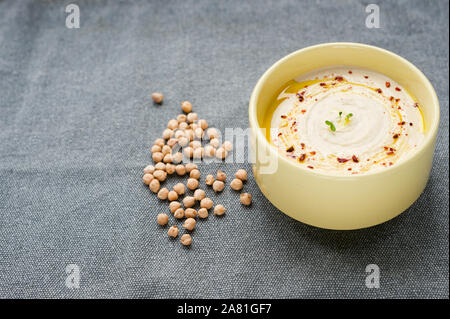 Hausgemachte cremigen Hummus mit Olivenöl und Gewürzen auf den textillle Hintergrund. Kichererbse Hummus. selektive Fokus, horizontal. Stockfoto