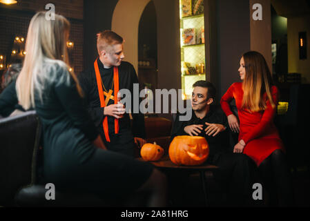 Junge Leute in Kostümen feiern Halloween. Urlaub Kürbis auf Tisch Stockfoto