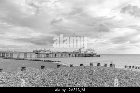 Früh morgens auf einem Kieselstrand in Eastbourne. Eine hölzerne Wellenbrecher im Vordergrund steht und ein Pier darüber hinaus. Eine Dämmerung Himmel über. Stockfoto