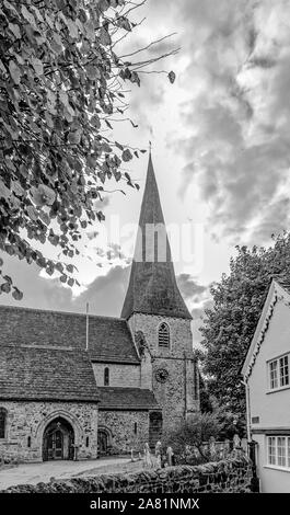 St. Mary's Kirche aus dem 13. Jahrhundert, Horsham mit einem Turm nach oben zu einem bewölkten Himmel. Ein Haus und Baum im Vordergrund. Stockfoto