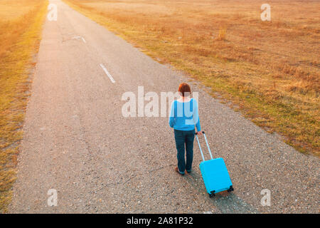 Frau ziehen Reisekoffer Koffer auf der Straße im Herbst Sonnenuntergang, hohen Betrachtungswinkel von Drone pov Stockfoto