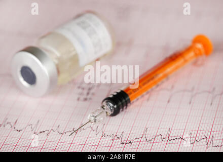 Spritze Durchstechflasche auf gedruckten Elektrokardiographen Stockfoto