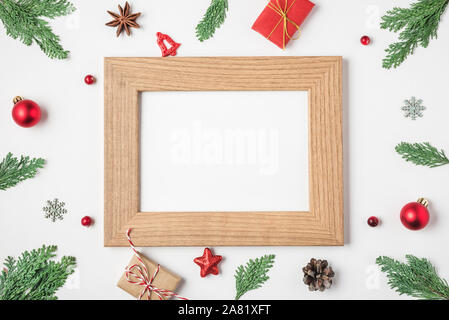 Leer Weihnachten Foto Karte im Rahmen der Fir Tree Branches, Geschenkboxen, rot Urlaub Dekorationen auf weißem Hintergrund. Mock up. Flach. top Aussicht wi Stockfoto