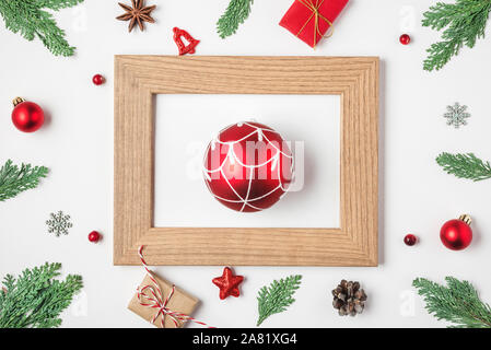 Weihnachten und ein glückliches Neues Jahr. Red Ball in Bilderrahmen mit Fir Tree Branches, rot Dekorationen und Geschenkboxen auf weißem Hintergrund. nach oben vie Stockfoto