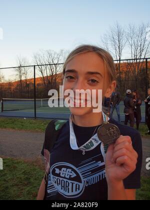 Elf Jahre alte Mädchen zeigt ihre ersten Platz Medaille kürzlich in einem Cross-country-Treffen. Immer noch lächelnd nach einem langen Lauf, war sie für ihre Bemühungen belohnt. Stockfoto