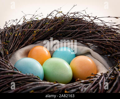 Ostern noch leben. Bunte eier in ein Nest auf einer hölzernen Oberfläche. Stockfoto