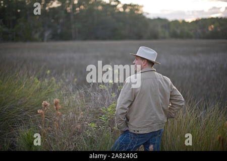 Mann mit einem fedora Hut und stehen in einem Feld Stockfoto