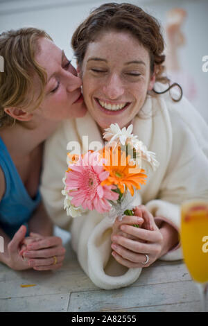 Frauen liegen auf dem Boden im Haus mit Orangensaft und Blumen Stockfoto