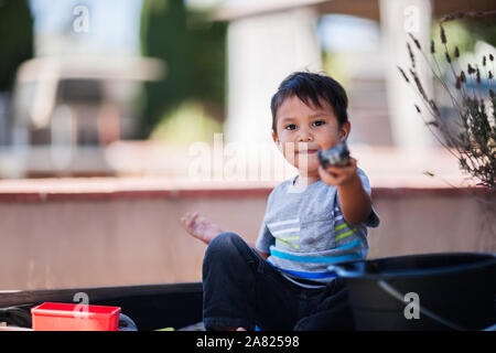 Ein Junge freundlich sein, indem sie ein Spielzeug während der Sitzung in einer Sandbox. Stockfoto