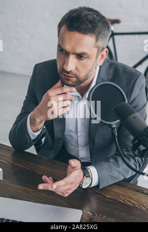 Nachdenklich radio host Gesten beim Sprechen in das Mikrofon in Rundfunk und Studio Stockfoto