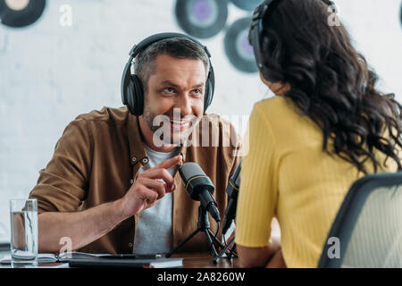 Lächelnd radio Host gestikuliert während im Gespräch mit Kollegen in Rundfunk und Studio Stockfoto