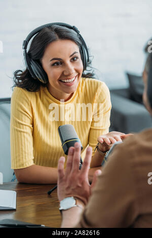 Attraktive radio Host lächelnd, während im Gespräch mit Kollegen in Rundfunk und Studio Stockfoto