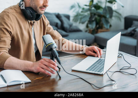 Blick auf Radio host mit Laptop, während in der Nähe von Mikrofon sitzen 7/8 Stockfoto