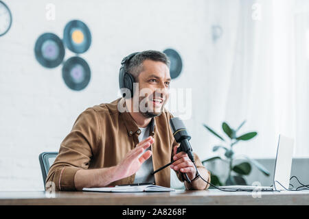 Freundliche radio Host gestikuliert während der Aufnahme podcast in Rundfunk und Studio Stockfoto