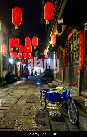 Ein blaues Fahrrad Warenkorb steht unter roten Laternen in einer Gasse von Fenghuang antike Stadt in Tibet, China hung leer. Stockfoto