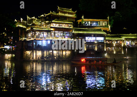 Eine Sampan Bootsfahrt führt Touristen durch die wässrige Passage der Tuo Jiang River in der Nacht in Fenghuang antike Stadt in Tibet, China. Stockfoto