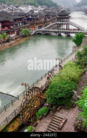 Einem malerischen Spaziergang entlang der Tuo Jiang River Höhepunkte der Charme der Alten Welt mit den Wasserrädern und gewölbte Nanhua Brücke in Fenghuang antike Stadt, in Stockfoto